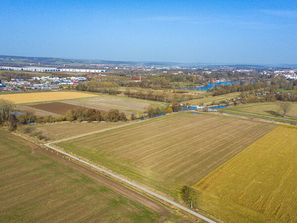 Die Biotoplandschaft am Flüthewehr in Göttingen vor den umgesetzten Maßnahmen. Aus der Vogelperspektive sieht man die noch intensiv genutzte Ackerfläche. Links und rechts sind weitere intensiv genutzte Ackerflächen. Am Horizont befinden sich einige Gebäude der Stadt Göttingen. Die Leine fließt durch dieses Areal.