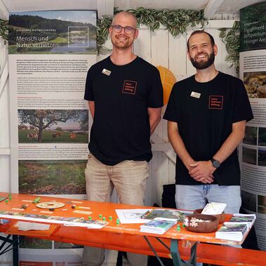 Carl-Christian Wippermann (rechts), Leiter der Biotopverbünde Südbayern und Mitarbeiter Andreas Nemetz am Stand der Heinz Sielmann Stiftung auf dem Tollwood Sommerfestival 2025.