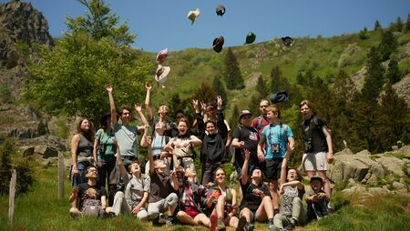 Eine Gruppe Jugendlicher steht zusammen und einige werfen ihre Mützen in die Luft